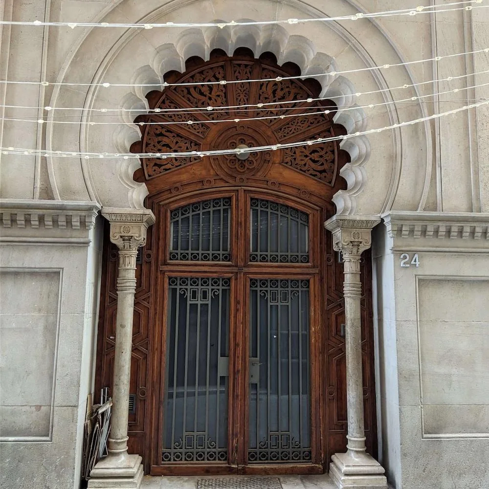 Clic per ampliar fotografia o plànol Porta principal de fusta tallada i arc polilobulat neomudèjar del Passatge Maria Canals al Passeig de Gràcia, 24